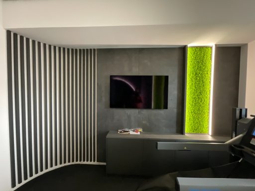 moderne Wandverkleidung Moderner Raum mit schwarzer Wand, TV, grüner Akzentbeleuchtung und minimalistischem Möbel.