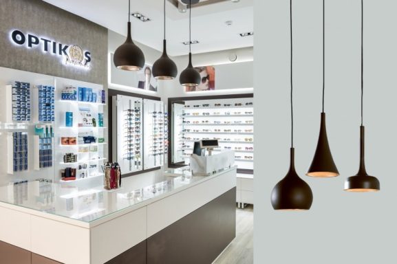 Verkaufstresen Modern Optiker-Geschäft mit eleganten, hängenden Leuchten und Brillenpräsentation.